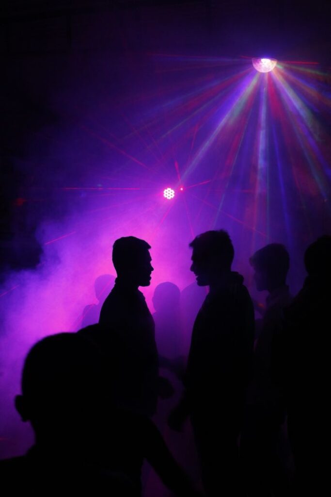 Veranstaltungen Silhouettes of people dancing under neon disco lights with a dramatic atmosphere.